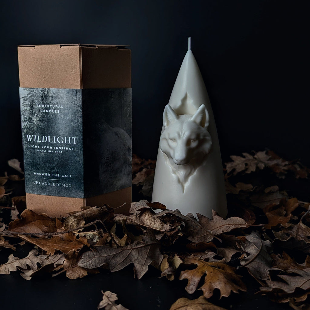 Candle with packaging on a dark surface with leaves